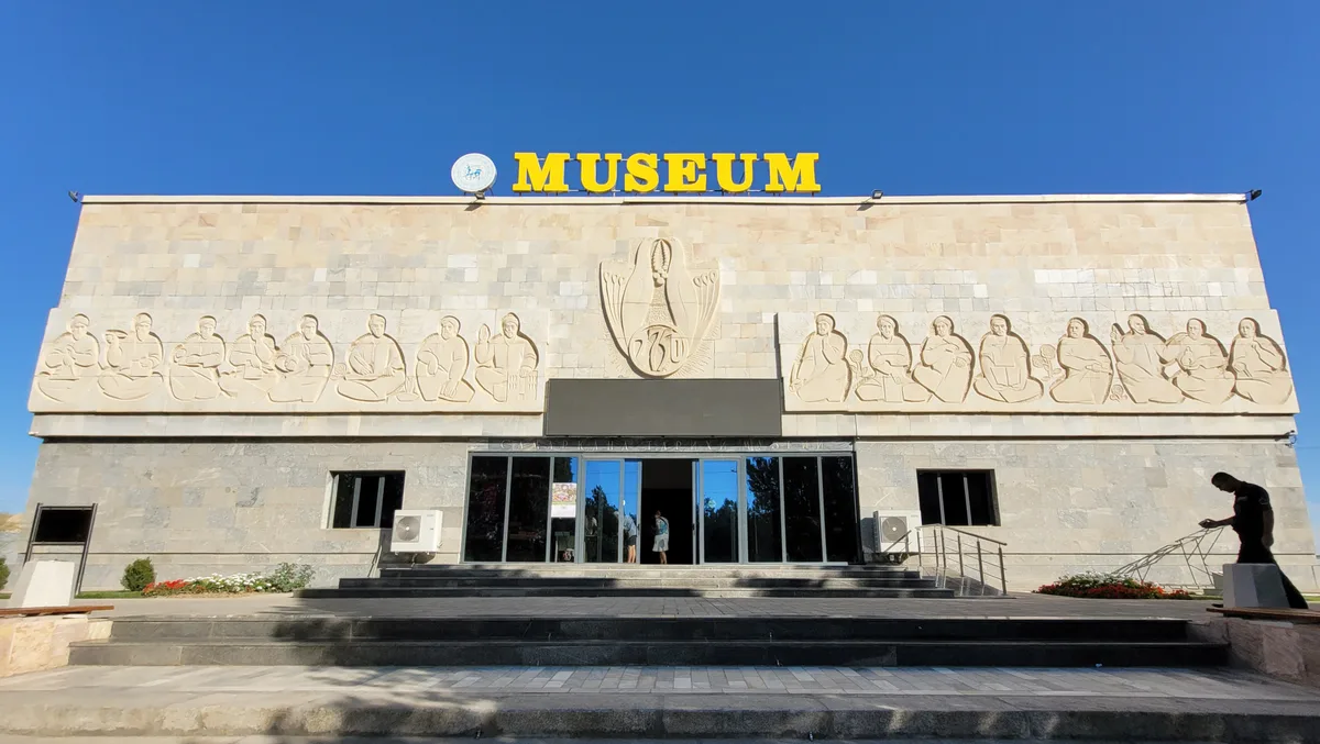 Afrasiab Museum in Samarkand - A two-storey modern building rises at the foot of a vast, bare archaeological mound of...
