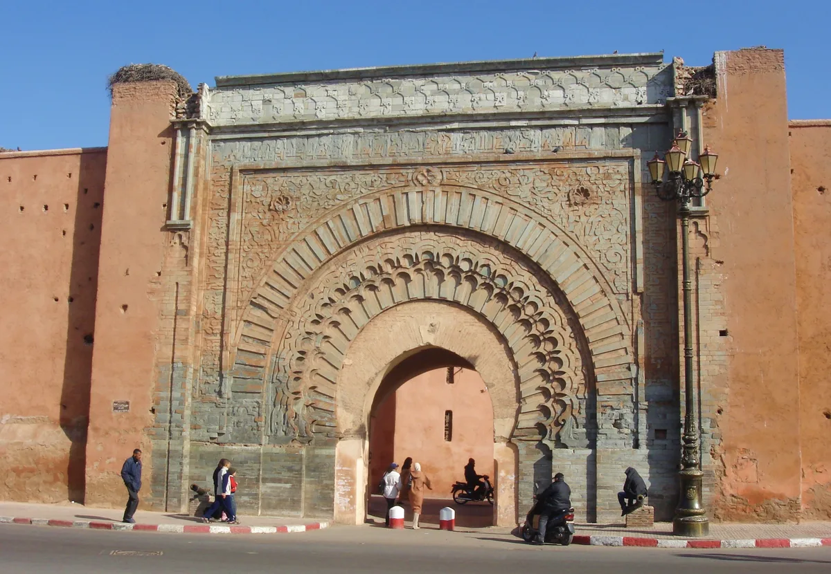 Agnaou Gate in Marrakech - A monumental stone gate with horseshoe arches, framed by carved floral and geometric reliefs...