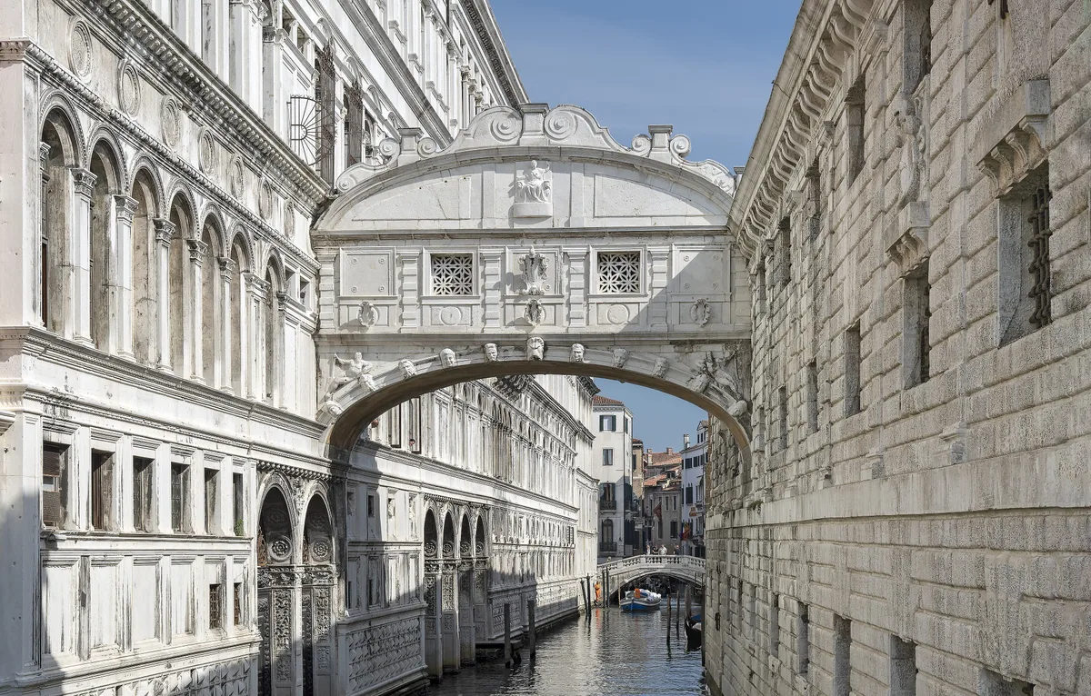 Bridge of Sighs in Venice - A small, fully enclosed white limestone bridge with two tiny windows barred by stone...