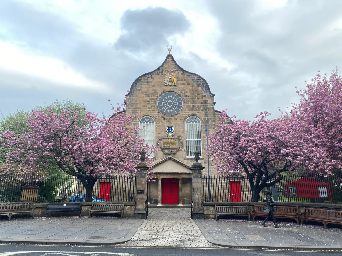 Canongate Kirk in Edinburgh - The plain 17th-century kirk on the Royal Mile with its Dutch gable, Doric portico and small bellcote, beside the kirkyard with the Mercat Cross