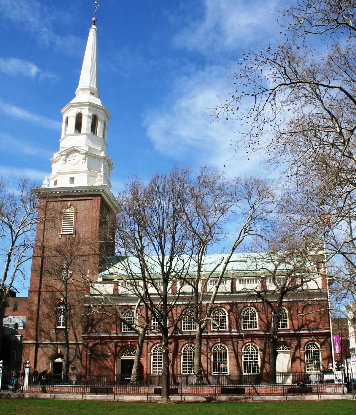 Christ Church in Philadelphia - A brick Georgian church with a tower and a landmark spire, set behind a low churchyard...