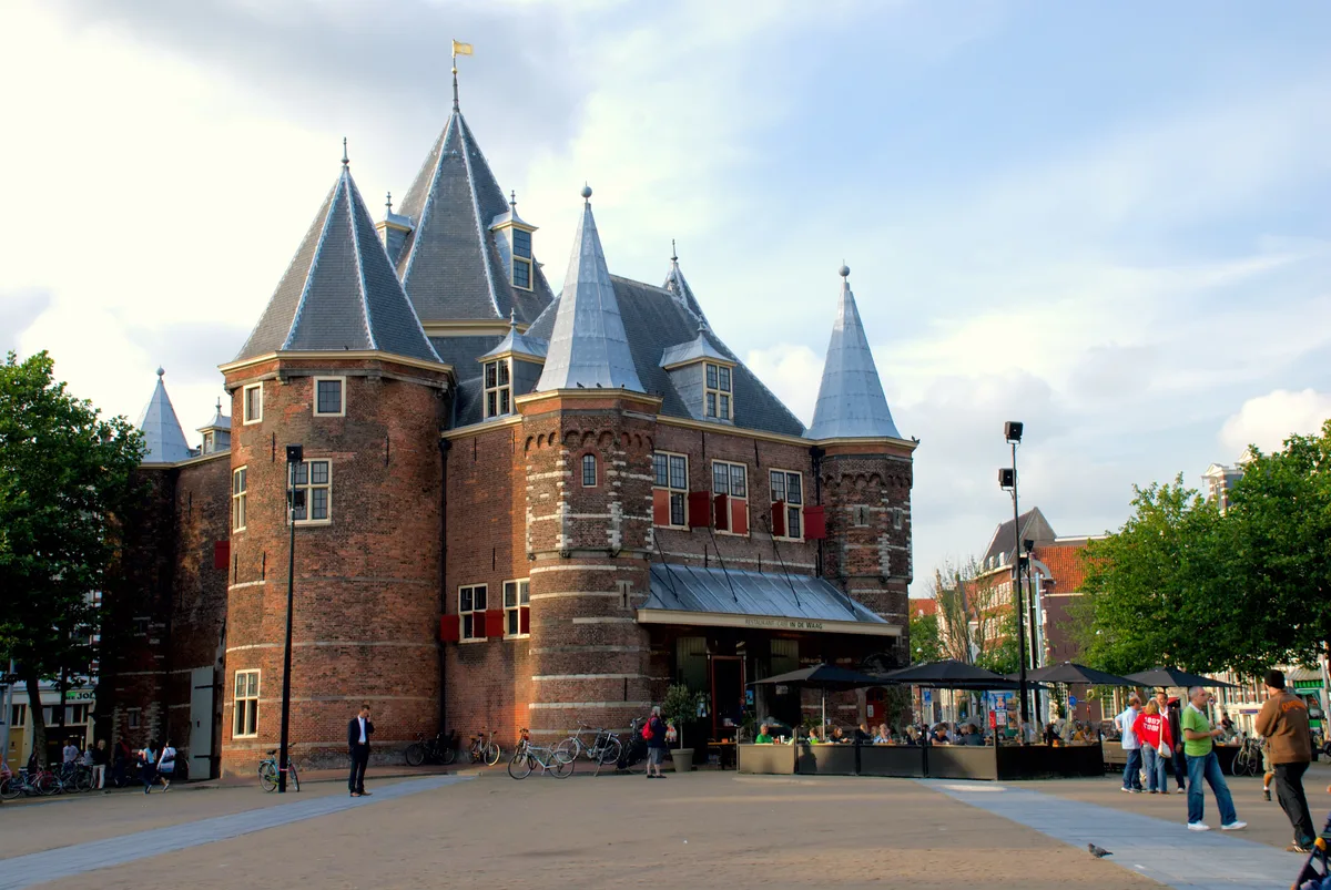 De Waag in Amsterdam - A stout brick city gate with five round towers rising above Nieuwmarkt square, its guild emblems...