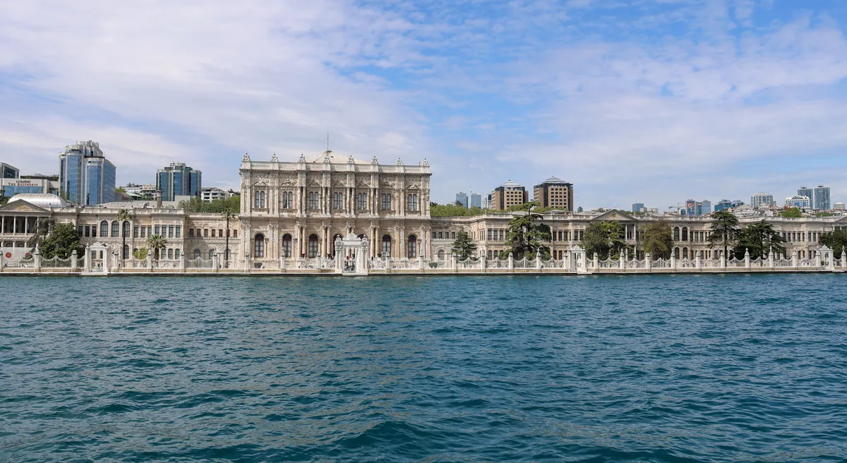 Dolmabahce Palace in Istanbul - A monumental, gleaming white marble facade stretching along the waters of the Bosporus...