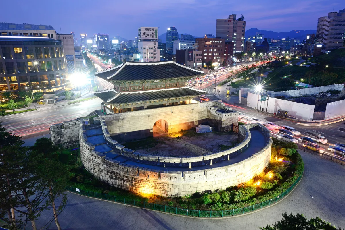 Dongdaemun in Seoul - A two-storey wooden gate with a tiled roof rising from a granite base, wrapped on its outer face...