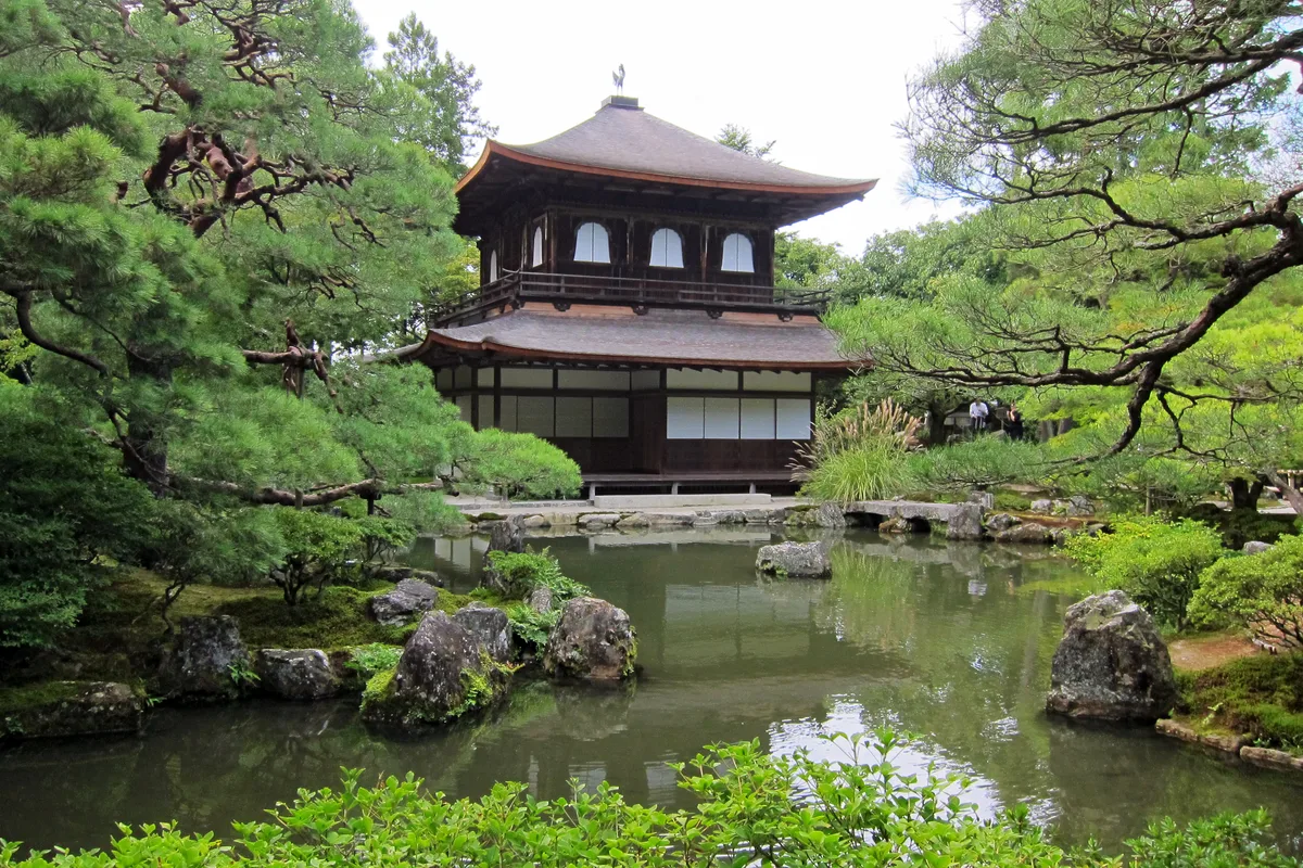 Ginkaku-ji in Kyoto - A modest, dark-wood two-story pavilion beside a meticulously raked sand garden and a sculpted...