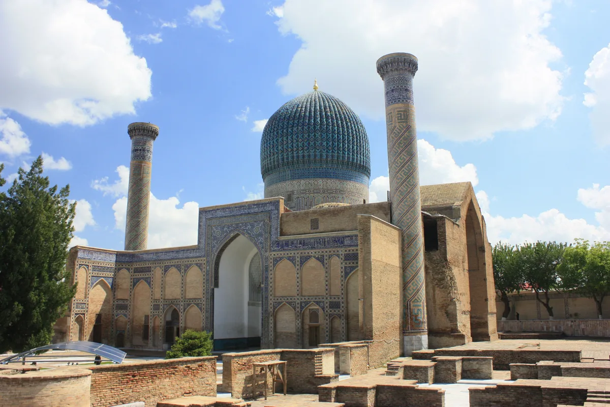 Gur-e-Amir Mausoleum in Samarkand - A ribbed, melon-shaped dome of turquoise tiles crowns a tall drum; below it, a...