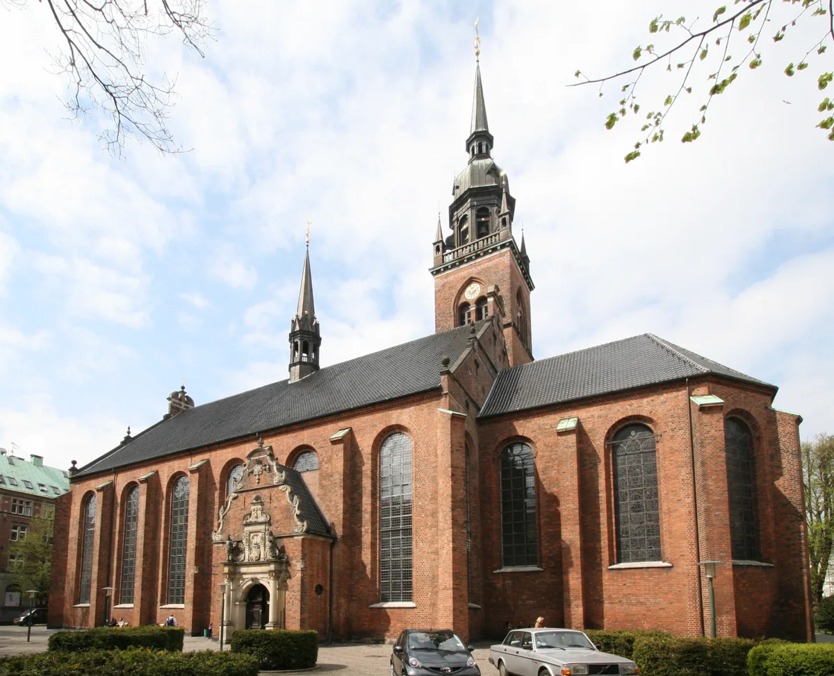 Church of the Holy Spirit in Copenhagen - A tall red-brick church with a stepped gable, squeezed between shops on the...