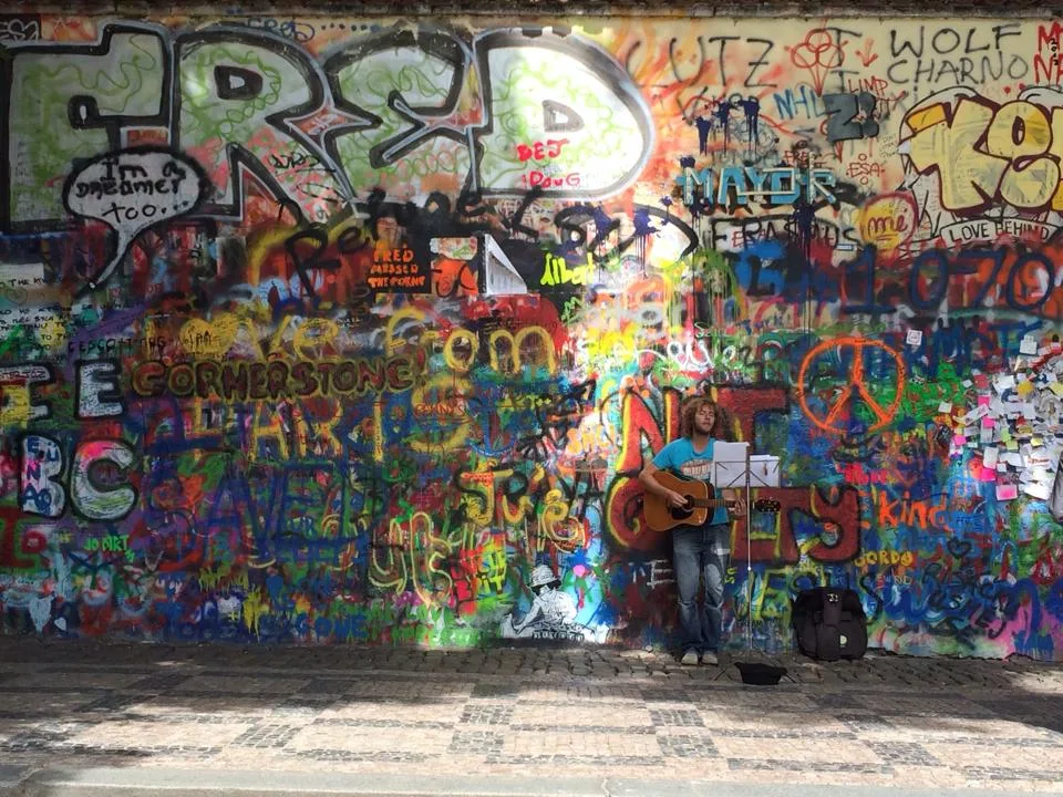 John Lennon Wall in Prague - A colourful wall covered in graffiti, lyrics, and peace symbols opposite the French...