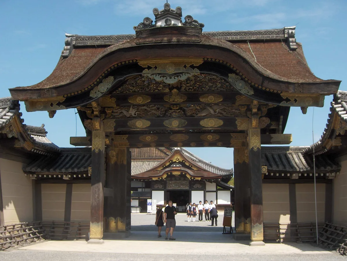 Nijo Castle in Kyoto - A sprawling castle complex surrounded by stone walls and wide moats, with ornate carved wooden...