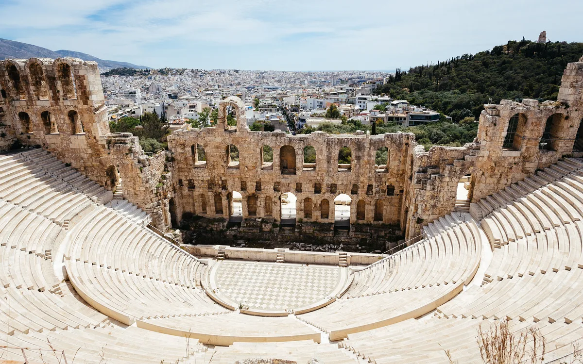 Odeon of Herodes Atticus in Athens - A steep stone amphitheatre with a tall arched rear wall nestled into the...