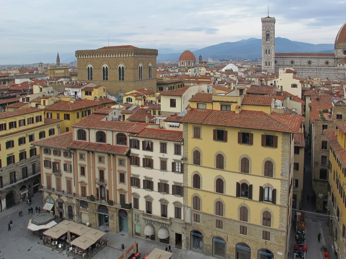Orsanmichele in Florence - A square stone building on a busy street corner, its upper storeys ringed by deep Gothic...