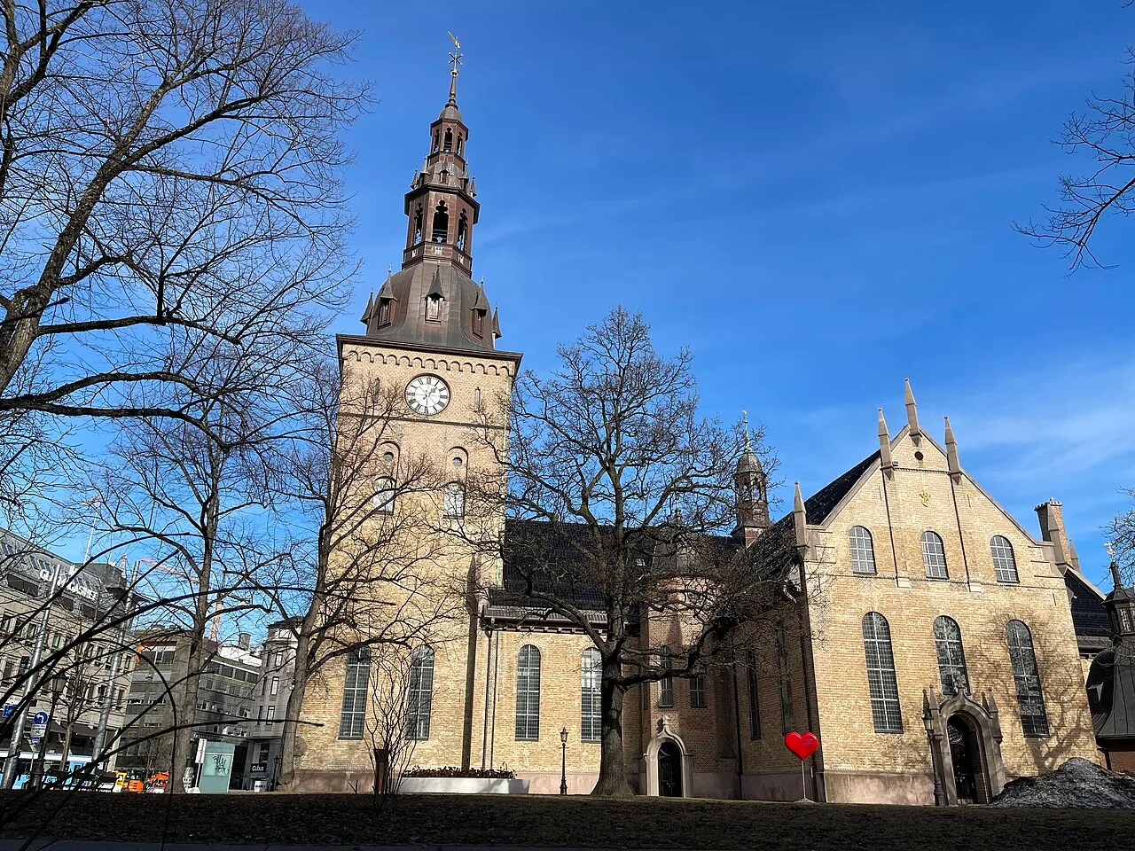 Oslo Cathedral in Oslo - A cruciform brick church with a tall west tower and copper-clad spire, raised on a rocky...