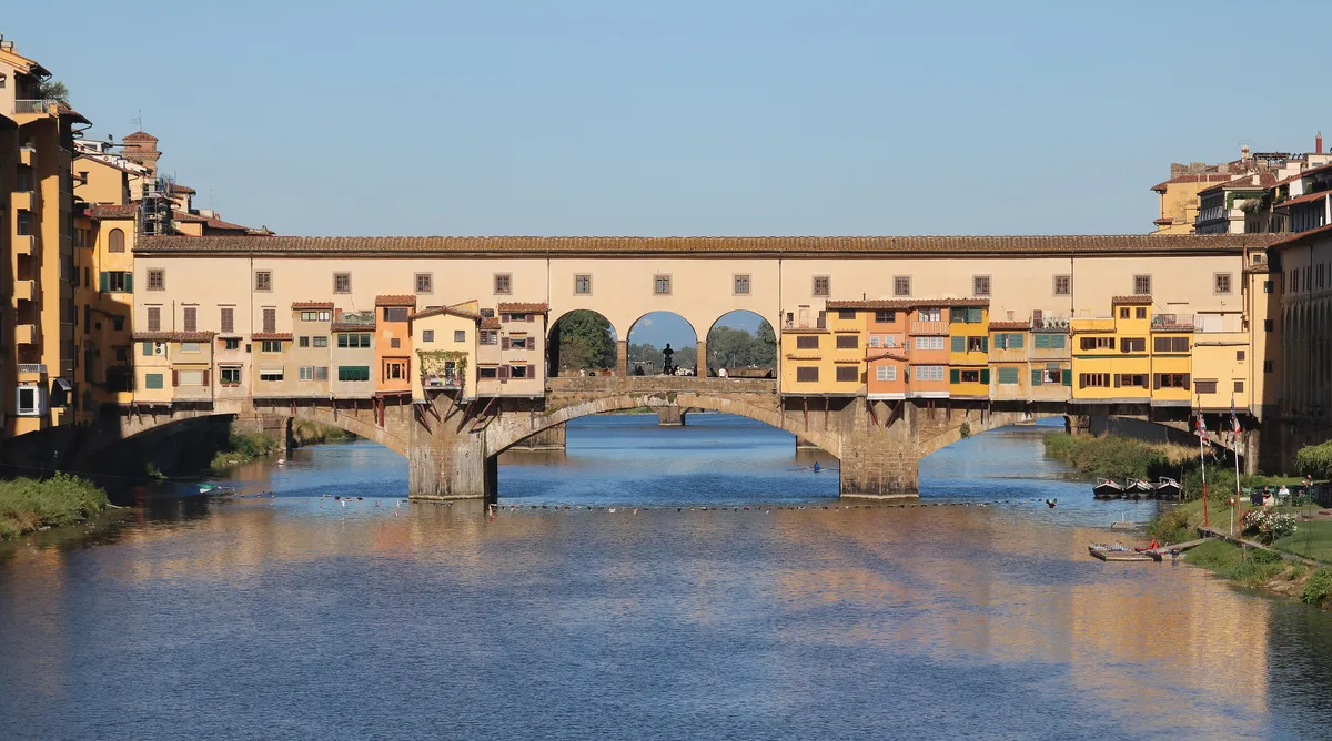 Ponte Vecchio in Florence - A low, three-arched stone bridge lined on both sides with rows of shops and topped on its...