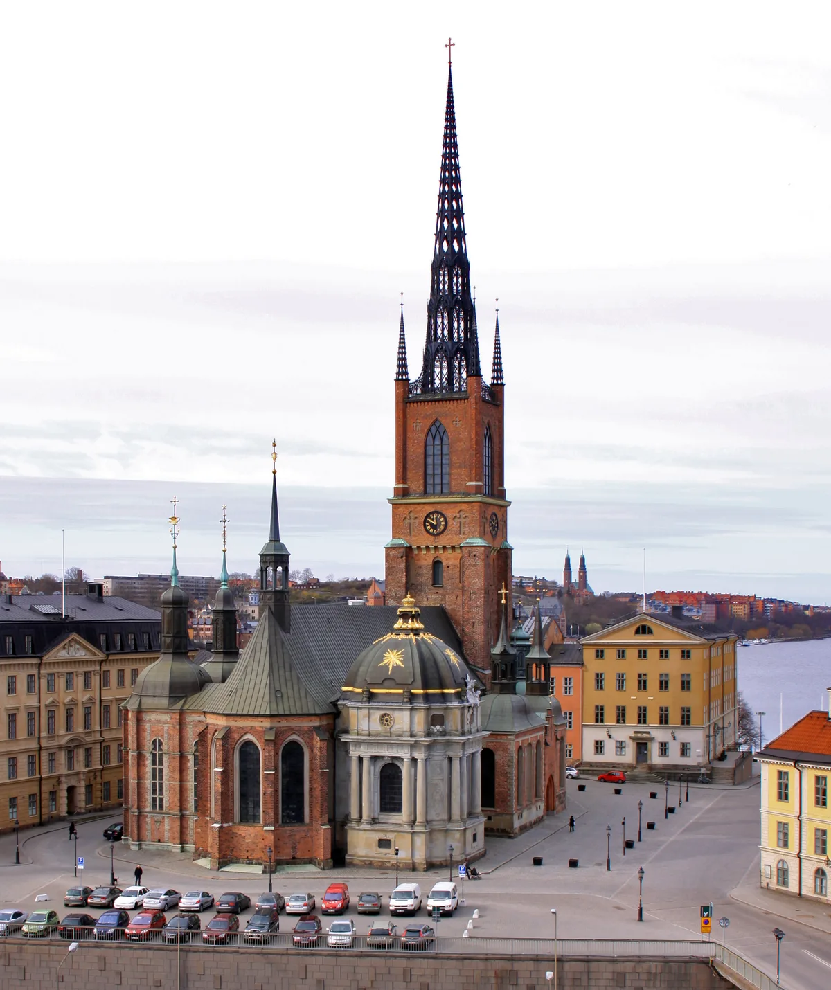 Riddarholmen Church in Stockholm - A long, dark-red brick church with a lacy cast-iron spire rising over the western...