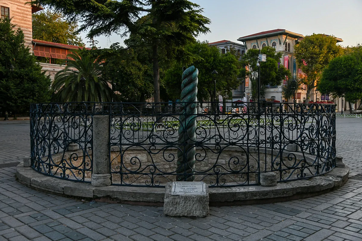 Serpentine Column (Yılanlı Sütun) in Istanbul - A dark twisted bronze column of three entwined snakes rising from a low stone base in the open ground of the old Hippodrome.