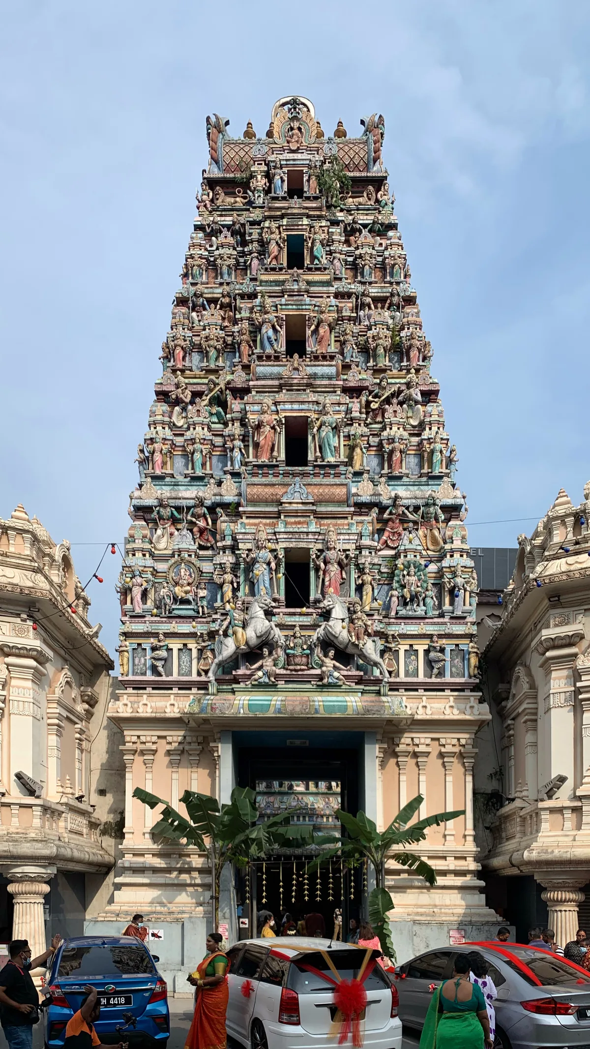 Sri Maha Mariamman Temple in Kuala Lumpur - A vividly painted South Indian temple rising behind a tall stone-carving...