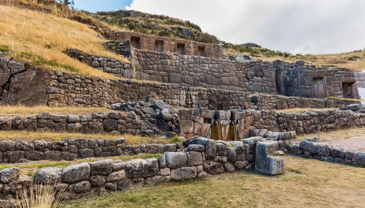 Tambomachay in Cusco - A hillside shrine of finely fitted stone terraces and trapezoidal niches through which spring...