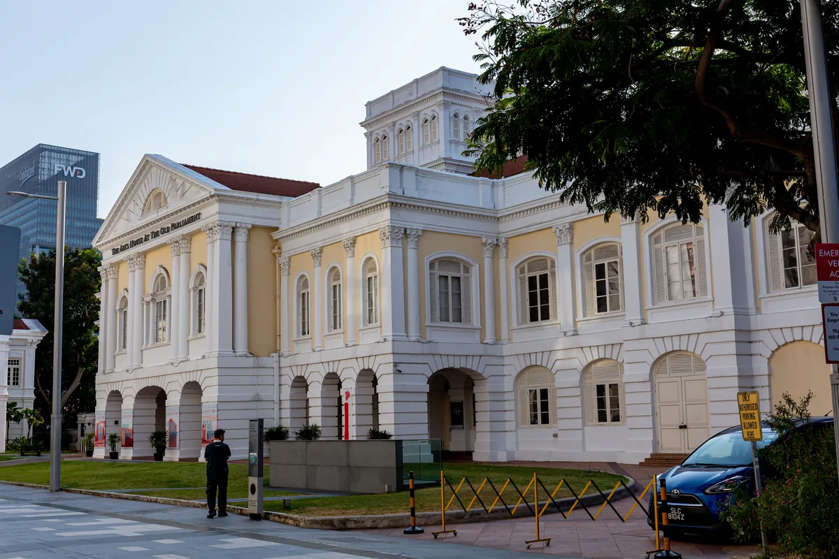 The Arts House in Singapore - A stately neoclassical building with a columned frontage and a low stone silhouette set...