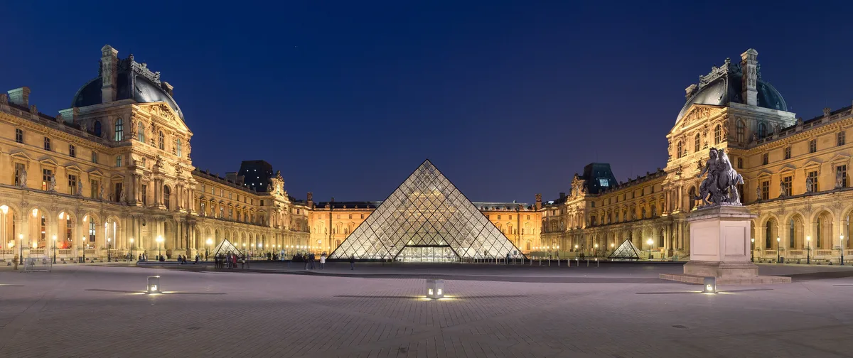 The Louvre in Paris - An enormous Renaissance and Baroque palace complex surrounding a square courtyard, with the...