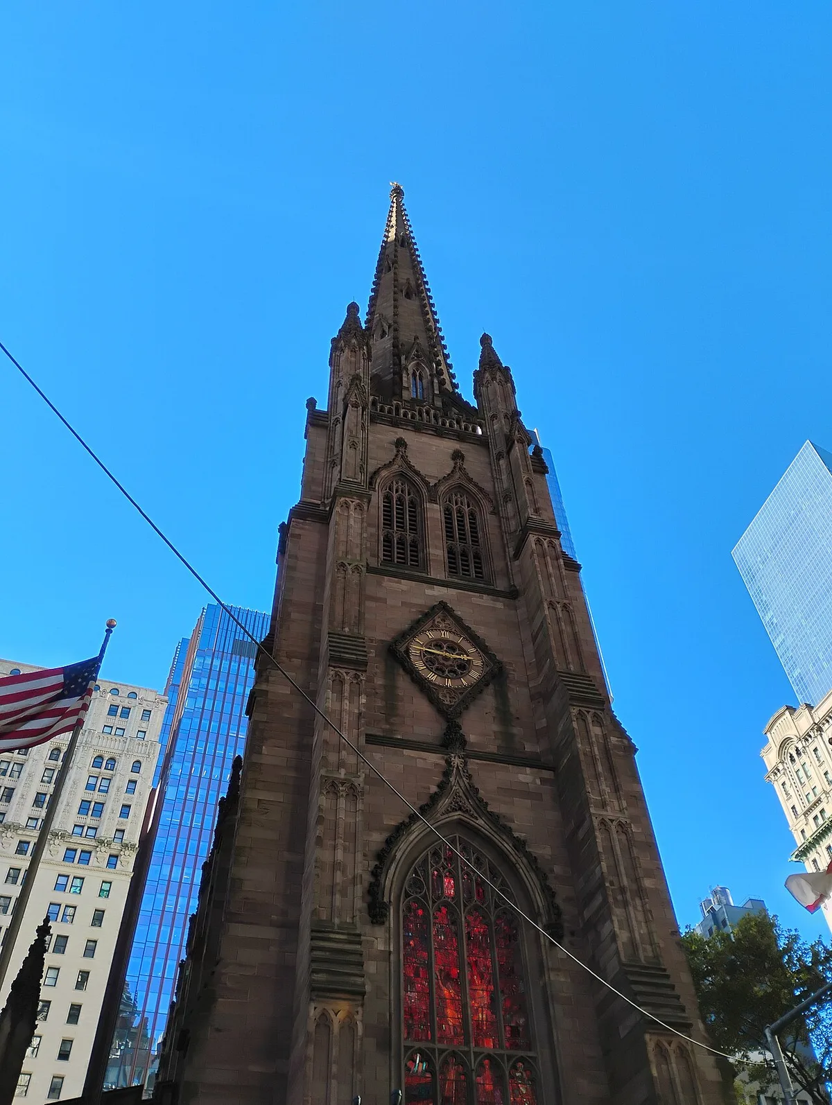 Trinity Church in New York - A brownstone Gothic Revival church with a tall single spire, rising above the glass towers...